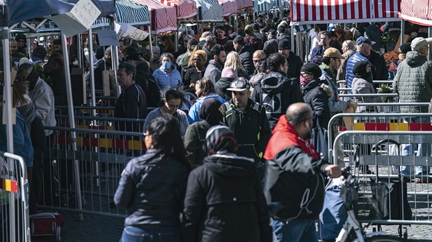 Lidé čekají ve frontě za přepážkami, které mají omezit fyzický kontakt mezi lidmi a usměrňovat pohyb davu. Jde o farmářské trhy ve švédském městě Malmö. 25. dubna 2020