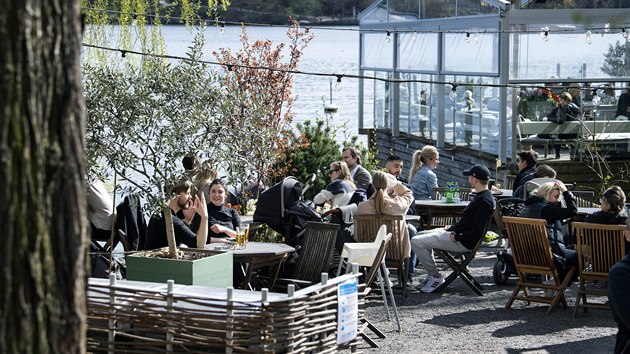 Obraz jak z jiné planety. Na zahrádce restaurace ve Stockholmu sedí lidé s rodinami. 26. dubna 2020