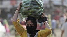 ena se zakrytými ústy a nosem nese zeleninu z trhu v Indii. (2.kvtna 2020)