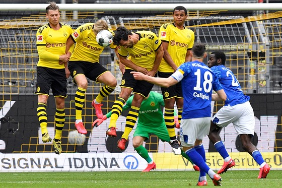 Fotbalisté Dortmundu ve zdi blokují stelu Daniela Caligiuriho z Schalke v...