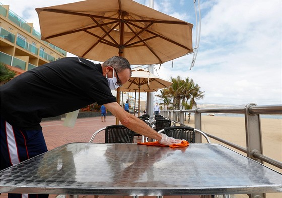 Číšník dezinfikuje stůl restaurace na pláži Las Canteras. (11. května 2020)