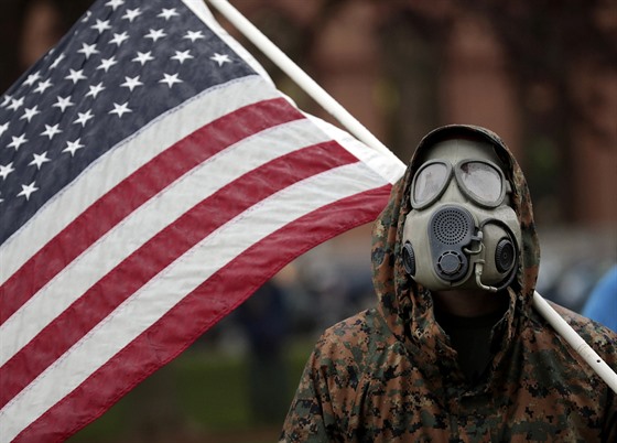 Protestující s plynovou maskou a americkou vlajkou nesouhlasí s vládními...