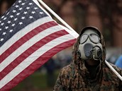 Protestujc s plynovou maskou a americkou vlajkou nesouhlas s vldnmi...