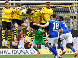 Fotbalisté Dortmundu ve zdi blokují stelu Daniela Caligiuriho z Schalke v...