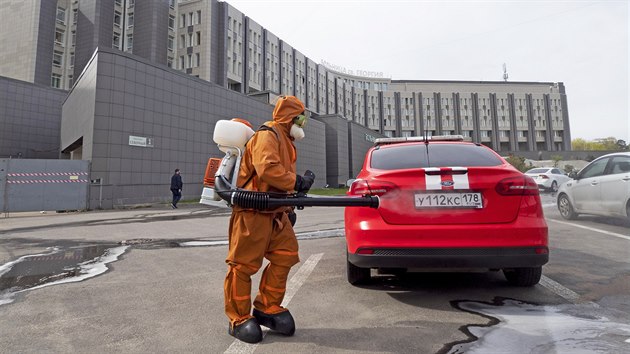 Muž v ochranném obleku dezinfikuje auto u Nemocnice svatého Jiří na severním předměstí Petrohradu, kde hořelo. (12. května 2020)