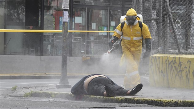Pracovnk v ochrannm obleku dezinfikuje tlo eny, kter se zhroutila a zemela pmo na ulici v Quitu, hlavnm mst Ekvdoru. (15. kvtna 2020)
