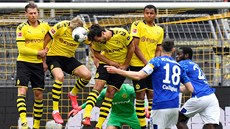 Fotbalisté Dortmundu ve zdi blokují střelu Daniela Caligiuriho z Schalke v...