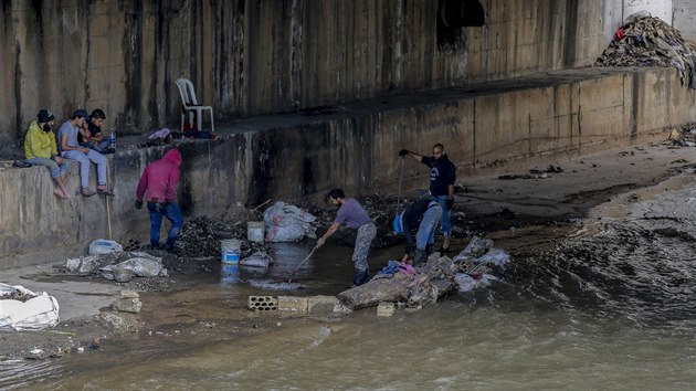 Muži hledají z kanalizace vyplavené cennosti v jedné z chudinských čtvrtí libanonského Tripolisu. (5. května 2020)