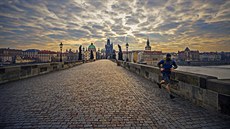 Osamělý běžec v roušce na liduprázdném Karlově mostě v prvních dnech karantény....