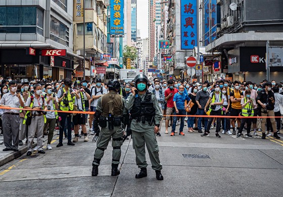 Policejní hlídka v Hongkongu zadruje dav protestující proti novému zákonu....