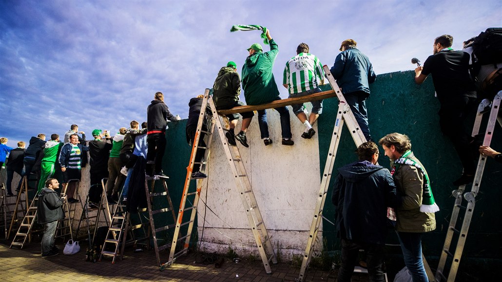 Fanoušci fotbalistů Bohemians sledují přes zeď stadionu v Ďolíčku ligový zápas...