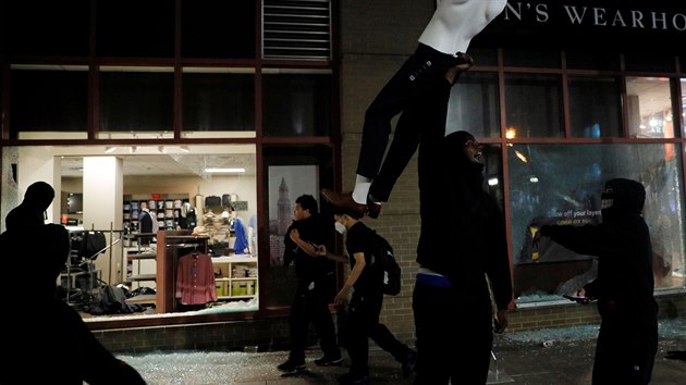 Demonstrant triumfln dr figurnu z obchodu, vyrabovanho bhem rasovch nepokoj v Bostonu. (31. kvtna 2020)
