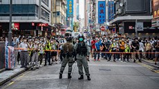 Policejní hlídka v Hongkongu zadruje dav protestující proti novému zákonu....