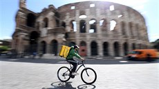 Poslíček na kole projíždí kolem Kolosea v Římě. (19. května 2020)