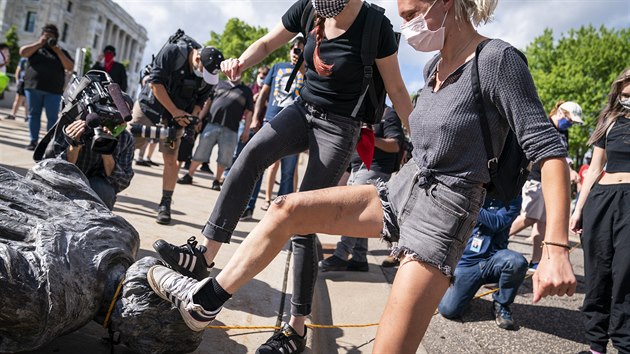 Demonstranti triumfln pokldaj nohy na svrenou sochu objevitele Ameriky Krytofa Kolumba ve mst Saint Paul ve stt Minnesota. (10. ervna 2020)