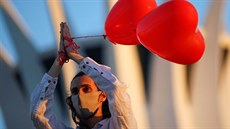 Umělec vystupuje s červenými balónky na počest lidí, kteří zemřeli s...