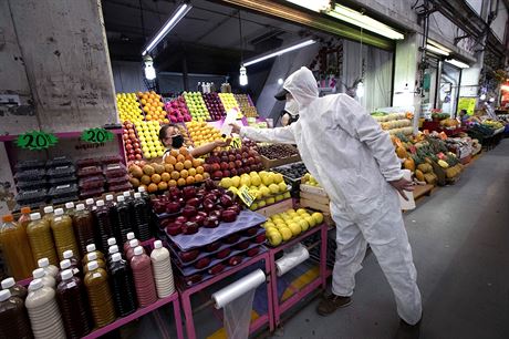 Zdravotník v ochranném obleku rozdává na trhu Central de Abasto v Mexico City...