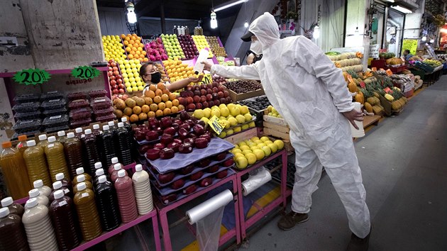 Zdravotnk v ochrannm obleku rozdv na trhu Central de Abasto v Mexico City dezinfekn gel. (18. ervna 2020)