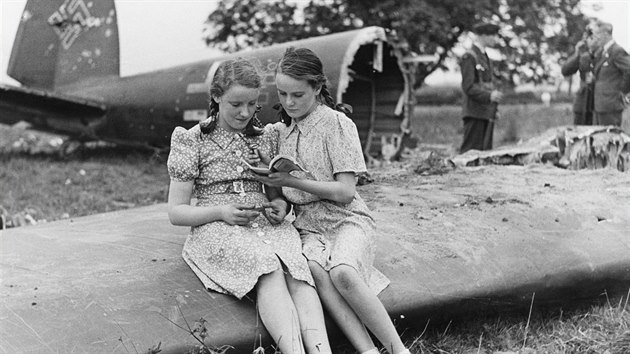 Dívky sedící na křídle zničeného německého bombardéru Heinkel He 111 kdesi v Anglii. (Bitva o Británii)