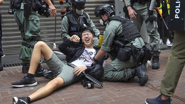 nt policist pomhaj mui zasaenmu pepovm sprejem pi protestech v centru Hongkongu. (1. ervence 2020)