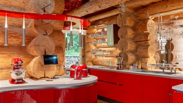Kontrastem ke dřevu je křiklavě červená kuchyňská linka, barva dřevo rozzářila a zdůraznila moderní ráz interiéru. V kuchyni nejsou horní skříňky a je vymyšlena tak, aby bylo při přípravě pokrmů vše při ruce.