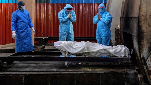 Příbuzní ženy, která zemřela v důsledku onemocnění covid-19 při modlitbě před kremací v indické metropoli Nové Dillí. (8. července 2020)