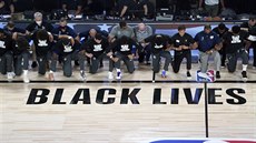 Basketbalisté New Orleans Pelicans a Utah Jazz klečí během hymny před zápasem...