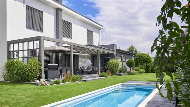 Moderní dům chrání před sluncem žaluzie, pobyt na terase zpříjemňuje velký slunečník a zastřešení.