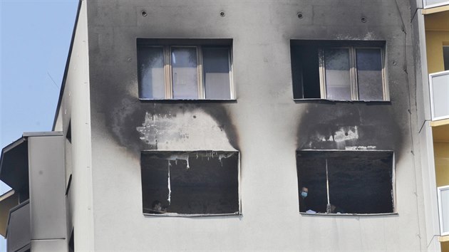 Okna vyhoelho bytu panelovho domu v Bohumn, kde pi poru zahynulo 11 lid. Policejn a porn vyetovatel byli na mst i druh den po poru. (9. srpna 2020)