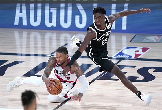 Damian Lillard (vlevo) z Portlandu ská�e po mí�i v souboji s Carisem LeVertem z...