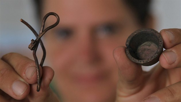 Vedoucí archeologického průzkumu Barbora Marethová ukazuje dva velmi cenné nalezené předměty ze zhruba 13. století: záušnici a kupecké závaží.