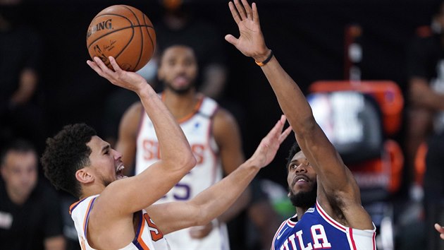 Devin Booker (vlevo) z Phoenixu zakonuje na ko Philadelphie kolem Glenna Robinsona III.