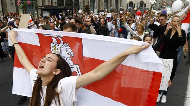 Žena s běloruskou vlajkou v davu demonstrujících, kteří vyšli na protest proti policejní brutalitě s níž zasahovali policisté na protestech v ulicích Minsku předchozí dny. (14. srpen 2020)