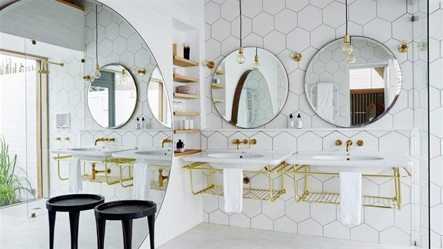 Modern koupelna v trendy bl a zlat kombinaci s temi obmi kruhovmi zrcadly kombinuje dva druhy obklad s litou podlahou. 