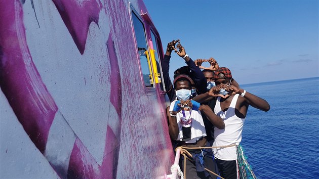 Migranti pózují na lodi Louise Michel, určené k záchraně migrantů ve Středozemním moři. Plavidlo financuje britský streetartový umělec Banksy. Loď zdobí výtvarníkovo dílo. (17. srpna 2020)