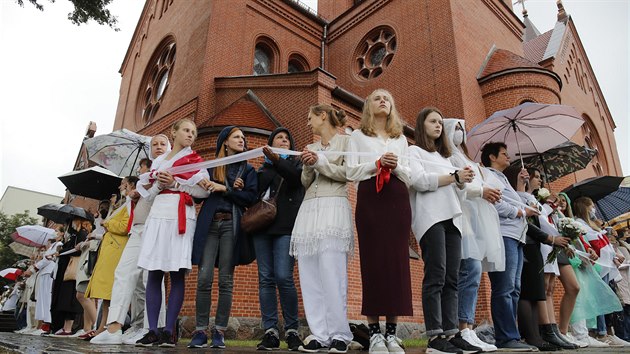 eny stojc v ad ped kostelem, dr blou stuhu, symbol protest proti bloruskmu prezidentovi Alexandrovi Lukaenkovi. (27. srpna 2020)