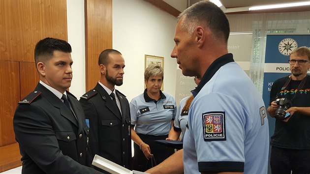 Krajský policejní ředitel Tomáš Kužel (vpravo) předává ocenění policistovi Radimovi Bílému, který se podílel na záchraně kolegy zasaženého bleskem. (24. srpna 2020)