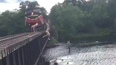 Mláde skáe do vody z mostu, kde projídí vlak