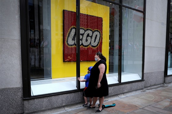 Žena s dítětem za výkladem uzavřené prodejny stavebnic Lego v Rockefellerově...