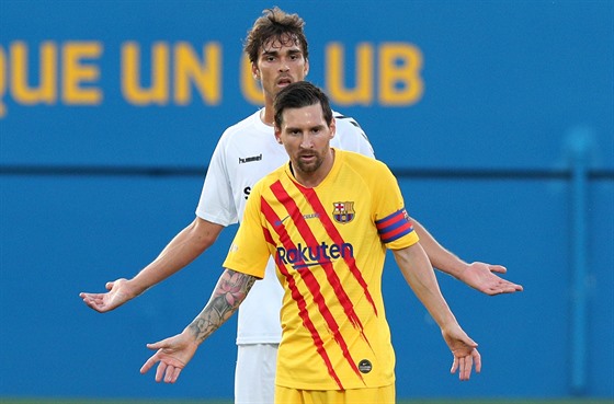 Lionel Messi z Barcelony v pípravném zápase s Gimnastic Tarragona, brání ho...