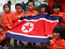 Dti drí ve kolce severokorejskou vlajku. (27. února 2019)