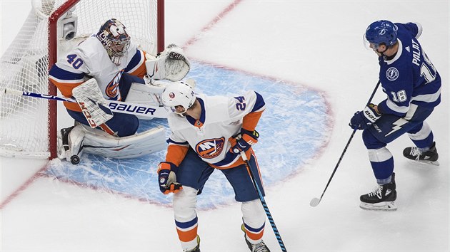 Ondej Palt (v modrm) z Tampa Bay se tla do zakonen v zpase s NY Islanders, Semjon Varlamov  vyr puk.