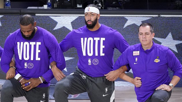 LeBron James, Anthony Davis a trenér Frank Vogel (zleva) z LA Lakers klečí při americké hymně.