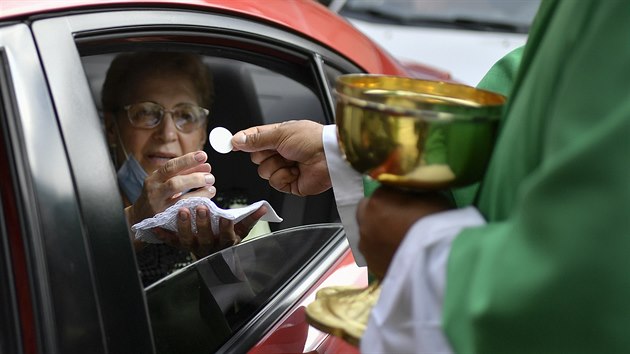 Otec Gonzalez podv en eucharistii na parkoviti ped kostelem ve venezuelskm Caracasu. Obchz tak koronavirov nazen zakazujc koncentraci lid v kostelech a chrmech. (26. jna 2020)