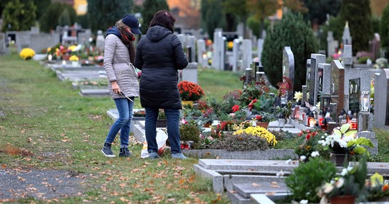 Lidé v rouškách zapalují svíčky na chebském hřbitově v předvečer dušiček...