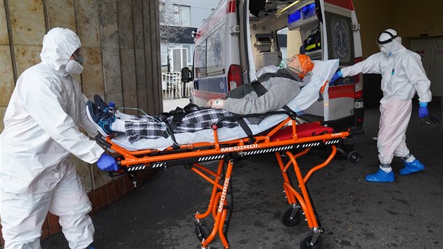 Zdravotnci v ochrannch oblecch pepravuj sanitkou pacienta s koronavirem do nemocnice ve Varav. (7. listopadu 2020 )