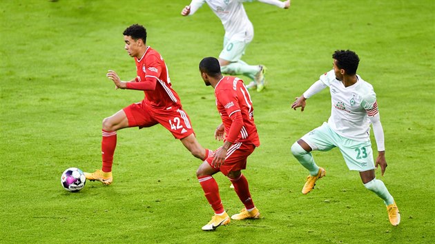 Jamal Musiala (vlevo) z Bayernu běží s balonem v zápase proti Brémám.