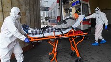 Zdravotníci v ochranných oblecích pepravují sanitkou pacienta s koronavirem do...