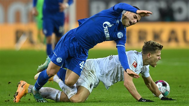 Can Bozdogan (v modrm) ze Schalke pad k zemi po stetu s Florianem Niederlechnerem z Augsburgu.