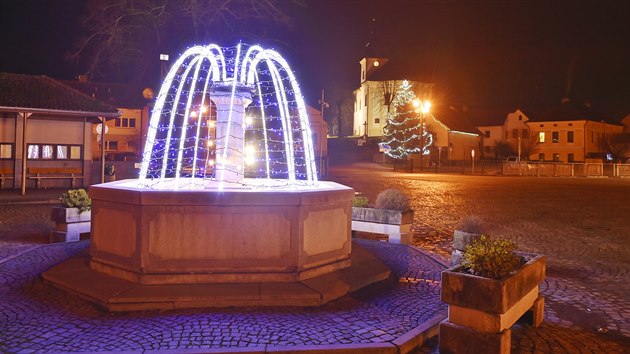 Kašna na náměstí v Lukách nad Jihlavou září namodralým světlem, evokujícím tryskání vody.